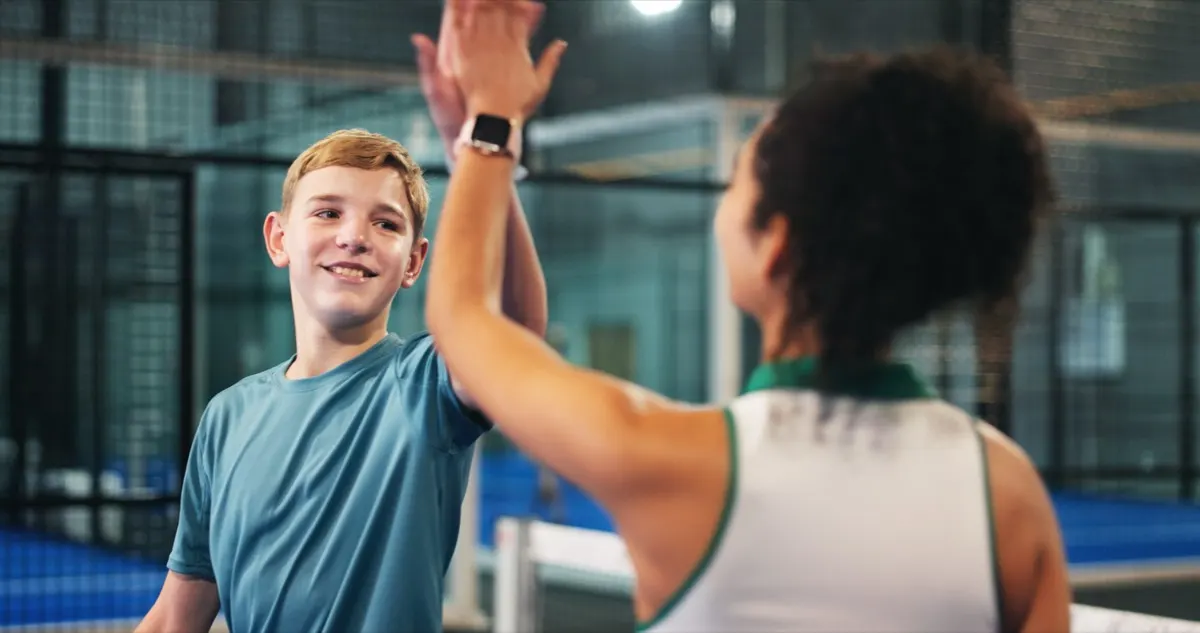 Two players high-fiving on an indoor padel court